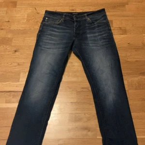 Jack & Jones Slim Straight Tim jeans - Mörkblå jeans från Jack & Jones i modellen Slim Straight Tim. Klassisk femficksdesign med snygga slitningar framtill och raka ben. Jeansen är tillverkade i bomull och har en stilren look med kontrastsömmar.