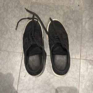 Svarta Arigato sneakers i mocka - Säljer ett par svarta sneakers från Arigato med snygg mocka-överdel och vit platt sula. Skorna har snörning och en stilren, rund tå. Perfekta för dig som gillar minimalistisk design och vill ha ett par schyssta sneakers med premiumkänsla. Pris kan diskuteras. De kommer att få en ordentlig tvätt innan den skickas.