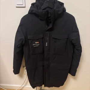 Svart dunjacka Sail Racing Gore-Tex - Svart dunjacka från Sail Racing med Gore-Tex-material, stor huva och flera praktiska fickor framtill. Jackan har dragkedja, knappar och snörning nedtill. Insidan är quiltad för extra värme och jackan har en clean, sportig look med logga på bröstet. Vanligt pris 6000. Kom dm för frågor 🧐pris kan diskuteras😁. 