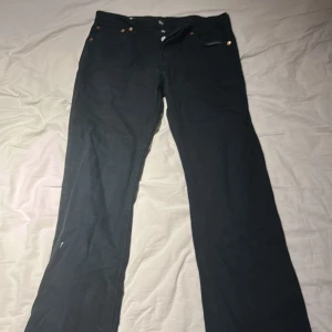 Svarta jeansbyxor med raka ben - Svarta jeansbyxor med klassisk femficksdesign och raka ben. Byxorna har knappgylf och detaljer i metall vid fickorna. Perfekta för en stilren och enkel look.