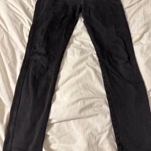 Svarta Replay Anbass jeans 32/34 - Säljer ett par svarta Replay Anbass jeans i storlek 32/34. Jeansen har klassisk femficksdesign, raka ben och snygga detaljer på bakfickorna. Materialet är mjukt och stretchigt för en bekväm passform. Perfekta för dig som gillar stilrena svarta jeans. På sista bilden syns slitningar vid insida lår men INGA hål!