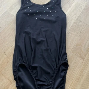 Svart gymnastik dräkt med diamanter - En svart gymnastikdräkt med rund halsringning och små glittrande stenar framtill. Klassisk modell med breda axelband och enkel rygg.