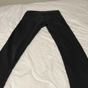 Svarta slim jeans från Jack & Jones - Svarta jeans från Jack & Jones i slim fit-modell. Klassisk femficksdesign med dragkedja och knapp framtill. Jeansen har en smal passform och är tillverkade i ett mjukt jeansmaterial som sitter snyggt längs benen.säljer pågrund av att de är för små. Använd fåtal gånger 