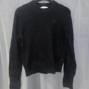 Svart stickad ylletröja från HOPE - Svart stickad tröja från HOPE med rund halsringning och långa ärmar. Enkel och stilren design som funkar till allt. 25% ull 17% mohair