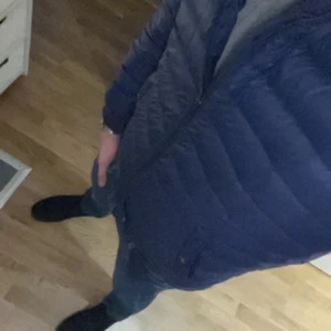 Mörkblå dunbomberjacka Polo Ralph Lauren - Säljer en mörkblå dunbomberjacka från Polo Ralph Lauren med ribbad krage och ärmslut. Jackan har dragkedja framtill, sidofickor med knappar och en patch med Polo-logga på ärmen. Perfekt för dig som gillar stilren och sportig look.