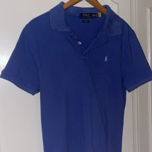 Blå pikétröja Polo Ralph Lauren - Klassisk blå pikétröja från Polo Ralph Lauren i slim fit-modell. Bra skick, 7-8/10. Barnstorlek XXL, passar S.
