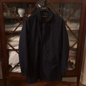 MooRER rock - Snygg mörkblå rock från MooRER med klassisk krage, knappstängning och tvåvägsdragkedja. Jackan har diskreta sidofickor och stilren design som passar dig som gillar cleana och tidlösa plagg. Perfekt för dig som vill ha en elegant look. Vattentät och perfekt för lager på lager under vintern. Köptes på Ströms våren 2025 för 10000kr. Lappar och allt finns kvar. Storlek 48 passar M!