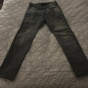 Replay svarta jeans med smal passform - Snygga svarta jeans från Replay med diskret tvättad look. Modellen har klassisk femficksdesign, smal passform och raka ben. Jeansen har bälteshällor, knapp och dragkedja framtill. Perfekta för dig som gillar stilrena och moderna jeans.