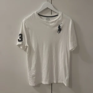 Vit Polo Ralph Lauren t-shirt S - Vit t-shirt från Polo Ralph Lauren i storlek XL. Klassisk design med svart broderad polospelare på bröstet och en svart siffra 3 på ärmen. Rund hals och korta ärmar. Tillverkad i mjuk bomull för skön känsla. Tröjan är S och funkar för mig som har S men är något stor i storleken