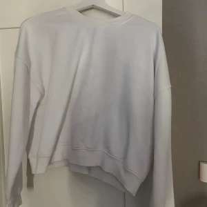 Vit sweatshirt från 157 i storlek M - Enkel och stilren vit sweatshirt från 157 med rund hals och långa ärmar. Tröjan har en relaxed passform och är gjord i mjukt material som passar perfekt till chill dagar. Klassisk modell utan tryck eller mönster.