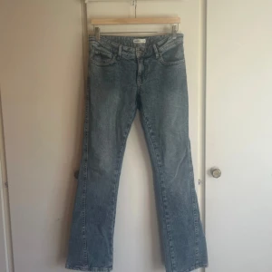 Blå bootcut jeans från Gina Tricot - Snygga blå jeans från Gina Tricot, modell Perfect Jeans. Bootcut passform med klassisk femficksdesign och coola broderade detaljer på bakfickorna. Jeansen har låg midja och är tillverkade i mjukt denimtyg för en skön känsla.