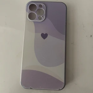 iPhone 12 Pro Max  -  iPhone 12 Pro Max med lila och beige skal med . Skalet har några mindre repor och slitage i hörnen, men annars i bra skick. Perfekt för dig som vill ha en personlig och skyddad mobil.
