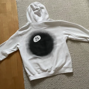 Eight Ball Hoodie - Vit Hoodie med tryck på ryggen / Tröjan har en liten gul fläck på luvan (se bild) utöver det så är den i bra skick!