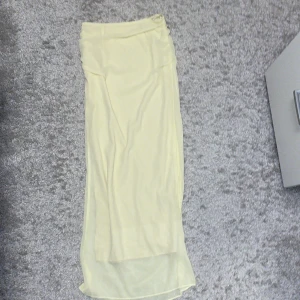 Ljusgul långkjol i chiffong - Säljer en ljusgul långkjol med flowig och lätt transparent chiffong-look. Kjolen har en enkel design med rak passform och mjukt fall. Perfekt för dig som gillar en feminin och luftig stil. Passar till sneakers eller sandaler.