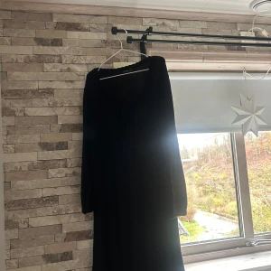 Svart lång stickad klänning Bodyflirt - Svart lång stickad klänning från Bodyflirt i storlek S. Klänningen har långa ärmar och en mjuk, ribbad rund halsringning. Perfekt för dig som gillar en enkel och stilren look med lite extra mysfaktor.