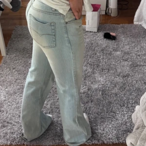 Ljusblå bootcut jeans - Säljer ett par ljusblå jeans med bootcut passform och klassiska fickor bak. Jeansen har en lätt tvättad look och är tillverkade i mjukt denimtyg. Perfekta för dig som gillar en avslappnad och trendig stil. Köpta second hand men inte använt dessa!! Finns ett jätte litet hål vid höger knä (se sista bild) men går säkert att sy ihop! 