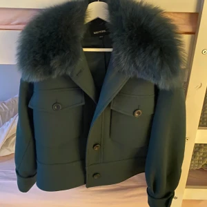 Mörkgrön pälsjacka från Meotine - Kan mötas upp i Stockholm Säljer en mörkgrön, croppad pälsjacka från Meotine med fluffig krage i pälsimitation. Jackan har stora fickor med lock och knappar framtill, samt långa ärmar och en loose passform. Perfekt för dig som vill ha en statementjacka med cool vibe.