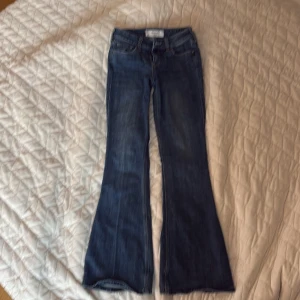 Blå low-rise flare jeans Hollister - Säljer ett par blå jeans från Hollister med låg midja och utsvängda ben. Modellen är Low-Rise Flare och har klassisk femficksdesign. Perfekta för dig som gillar retrovibbar och snygg passform. Materialet är jeans i bomull.