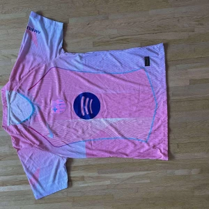 Rosa FC Barcelona fotbollströja Nike - Säljer en rosa FC Barcelona fotbollströja från Nike med Spotify-logga på bröstet och UNHCR-tryck på ryggen. Tröjan har korta ärmar, tunna vita och blå linjer samt klubbmärke på framsidan. Materialet är lätt och andas, perfekt för match eller träning.