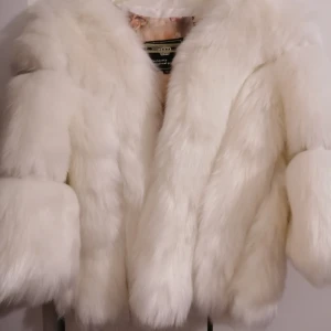 The beauty optimal product - vit fluffig pälsjacka  - Säljer en superfluffig vit pälsjacka i storlek M från The beauty Optimal product. Jackan har en lyxig känsla med mjuk pälsimitation och ett insytt foder med coolt tryck av parfymflaskor och text. Perfekt för dig som vill sticka ut med en statement jacka. Ops: armarna är inte hela vägen ned, utan armarna är korta. Storlek är M, dock sitter den perfekt på mig som är XS. Har ALDRIG används. Taggen finns dock inte kvar! 😊