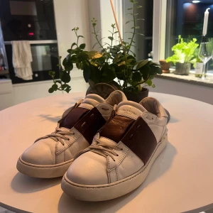 Valentino open - Säljer ett par Valentino Open i vitt och vinrött 100% äkta och i bra skick – bara normalt bruksslitage, inget större. Väldigt bekväma och passar till det mesta.  📏 Storlek: 43 🎨 Färg: Vit/vinröd 🧾 Nypris: ca 6 000–7 000 kr  Skickas snabbt och välpackat. Hör av dig om du vill ha fler bilder eller frågor!