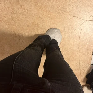 Svarta cargopants med bootcut - Säljer ett par jättefina svarta  bootcut och låg midjade jeans. Byxorna har fickor med knapp på sidorna och två knappar i midjan. Säljer pga att de blivit lite för små för mig🩷💕