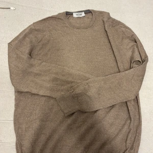 Beige stickad tröja från Gran Sasso - Säljer en stilren beige stickad tröja från Gran Sasso. Tröjan har rund halsringning, långa ärmar och ribbade muddar. Perfekt för lager-på-lager och enkel att matcha med jeans eller chinos.