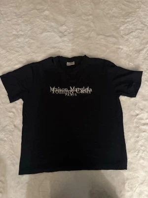Maison margiella Tommy cash T-shirt  - Skick: använd mycket men finns liv kvar i den! Detaljer: 	•	Färg: svart 	•	Material: bomull  	•	Passform: oversized fit 	•	storlek: m (Passar medium)  Plagget kommer från rök- och djurfritt hem.  📦 Frakt: skickas samma dag om köp går igenom innan 18.00 💬 Frågor: Hör av dig om du vill ha fler bilder eller mått 🤝 Paketpris: Samfraktar gärna vid flera köp OBS: har tidigare varit en lapp på vänster sida av kragen som stuckit ut från ett hål men lappen är bortklippt