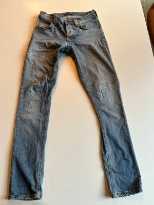 Nudie Jeans Grim Tim - Tjena, jag säljer ett par Nudie Jeans, de är i modellen grim tim och storleken 30/32. De har lite slitningar på benen och har blivit lagade i grenen, vid fler frågor hör av er! Pris ej hugget i sten! 😊