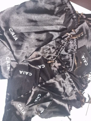 Svarta sminkpåsar från CAIA - Sminkpåsar i siden från CAIA med tryck. Perfekta för att förvara sminkborstar, beautyblenders eller smycken & solglasögon i. Påsarna har dragsko i sidenliknande material och är riktigt snygga att ha i sminkväskan. Olika storlekar 10 kr st