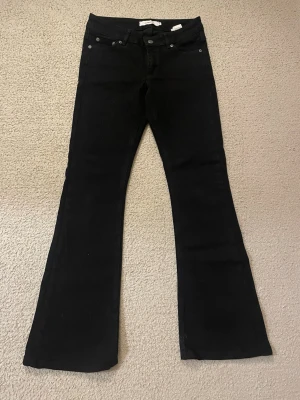 Svarta bootcut jeans Junkyard XS - Säljer ett par svarta bootcut jeans lågmidajde från Junkyard i storlek XS. Jeansen har klassisk femficksdesign, raka ben som blir vidare nedtill och snygga sömdetaljer på bakfickorna. Materialet är jeans med en mjuk känsla och stretch. Helt nya men var lite för små när ja testade, så aldrig använt! 