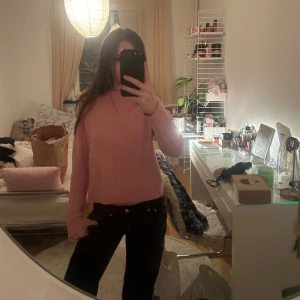 Ljusrosa stickad tröja - Supermysig ljusrosa stickad tröja med rund hals och ribbade muddar. Tröjan har en enkel och clean look, perfekt att slänga på sig när det är lite kyligt. Passformen är normal och den är långärmad. Snygg till både jeans och kjol!