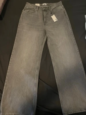 Grå wide leg jeans från Boulevard XL - Säljer ett par gråa high rise jeans från Boulevard i storlek XL. Byxorna har breda ben och klassisk femficksdesign. Materialet är jeans och färgen är en snygg tvättad grå ton. Perfekta för dig som gillar loose och relaxed fit.