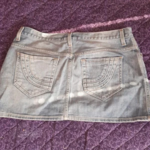 Ljusblå jeanskjol med fickor - Snygg ljusblå jeanskjol med klassiska fickor både fram och bak samt bälteshällor. Kjolen har en rak passform och stängs med knapp och dragkedja framtill. Perfekt för dig som gillar en enkel men trendig stil. Älskar den men säljer den då den tyvärr ej passar mig. 