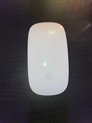 Apple Magic Mouse - Snygg och stilren Apple Magic Mouse i vitt och silver. Trådlös Bluetooth-mus med touchyta för smidig navigering. Några mindre ytliga repor och smuts, men i gott skick och fullt fungerande. Perfekt till MacBook eller iMac.