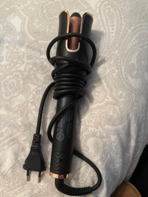 Automatisk locktång  - Säljer en snygg locktång i svart med detaljer i roséguld. Den har flera värmeinställningar (160°C-220°C) och en smidig design med greppvänligt handtag. Perfekt för att fixa lockar snabbt och enkelt. Passar till europeisk elkontakt.