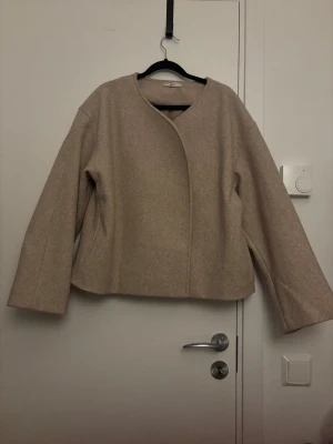 Round neck short jacket från Gina Tricot - Snygg beige skepparjacka från Gina Tricot med rundad hals och dubbelknäppning framtill. Jackan har en loose passform och är tillverkad i polyester. Endast provad. 