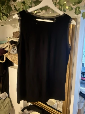 Svart ärmlös topp från Esprit XL - Säljer en svart ärmlös topp från Esprit i storlek XL. Toppen har en enkel och stilren design med transparenta meshdetaljer vid halsringningen och axlarna. Perfekt att styla med jeans eller kjol för en clean look.