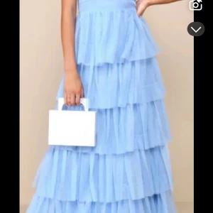 Ljusblå långklänning med volanger - Säljer en drömmig ljusblå långklänning med flera lager av volanger. Använd en gång. Köpt för 2tusen!  Klänningen har smala axelband och en omlott-design vid bysten som ger en elegant touch. Perfekt för speciella tillfällen! 💙 Använde vid balen och säljer för 1000kr. Storlek 34 men passade mig som är 34/36. Från lulus💙