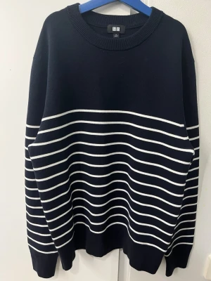 Randig svart tröja från Uniqlo - Säljer en svart tröja från Uniqlo i storlek S med vita horisontella ränder. Tröjan har rund halsringning, långa ärmar och ribbade muddar. Perfekt för dig som gillar klassisk stil med en modern twist.
