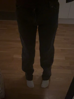Mörkgråa raka jeans - Säljer ett par gamla mörk gråa jeans med rak passform och klassisk femficksdesign. Jeansen har normal midja och stängs med knapp och dragkedja. Perfekta till en avslappnad stil och funkar året runt. 