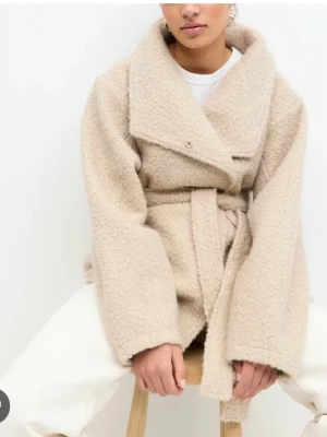 Beige teddyjacka med bälte - Säljer en beige teddyjacka med bred krage och knytbälte i midjan. Helt ny med prislapp! 