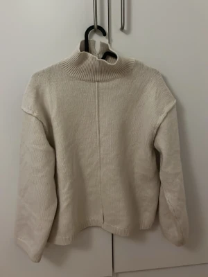 Stickad polotröja från H&M - Mysig beige stickad polotröja från H&M i storlek XS. Tröjan har en hög ribbad polokrage, långärmad passform och är gjord i ett mjukt material som passar perfekt till kyligare dagar. Enkel och clean design som är lätt att matcha.