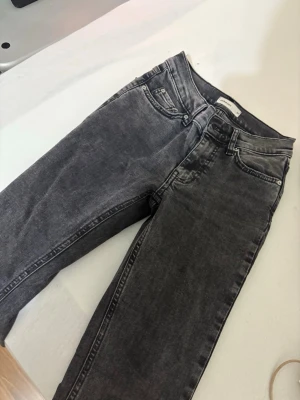 Mörkgrå raka jeans - Säljer ett par mörkgrå jeans med klassisk femficksdesign och raka ben. Jeansen har en snygg tvättad look och normal passform. Perfekta till sneakers eller boots och funkar året runt.