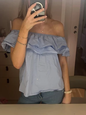 Ljusblå offshoulder volangblus  - Säljer en ljusblå blus med offshoulder💗har en liten fläck som man kan se på bilden 