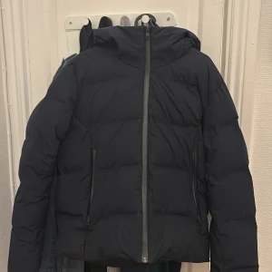 Svart pufferjacka från Uniqlo XS - Säljer en svart pufferjacka från uniqlo i storlek XS. Jackan har luva och är i ett bra skick. Den har inga skador och håller bra.