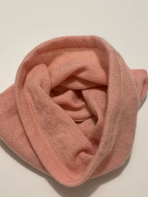 Ljusrosa kashmir buff - Supersöt ljusrosa buff i 100% kashmir. Enkel och clean design utan mönster eller detaljer, perfekt att dra över huvudet för extra värme. Passar till alla dina vinterlooks och är riktigt skön mot huden.