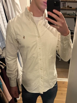 Vit skjorta från Ralph Lauren - Klassisk vit skjorta från Ralph Lauren med broderad logga på bröstet. Skjortan är lite offwhite färgad enligt mig.