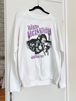 Vit Håkan Hellström Merch Ullevi 2022 sweatshirt, storlek M - Officiell Håkan Hellström Ullevi 2022 merchendise som inte säljs längte.  Text i lila och svart grafiskt motiv framtill, rund halsringning och långa ärmar. Använd en handfull gånger. Sann till storleken.  #håkan #hellström #håkanhellström #håkanhellström #håkanhellströmlive #håkanhellströmfans #ullevi #merch #merch2022 #2022 #sweatshirt #vit #lila #svart #håkanhellströmkonsert