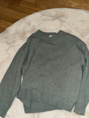 Grå/ grön stickad tröja från H&M - Mysig grå stickad tröja från H&M med diskreta små pärlor över hela tröjan